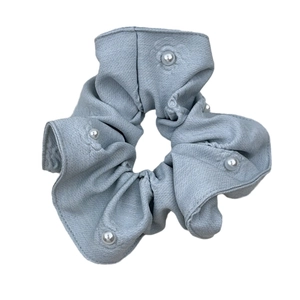 Chic light blue denim scrunchie with white pearl embellishments and soft fabric texture