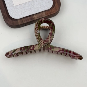 Detailed top view of a large red and green plaid hair claw clip on a white surface