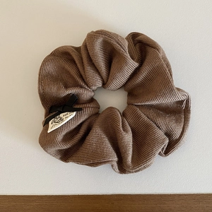 Close-up of brown knit scrunchie with a black bow and handmade fabric label details
