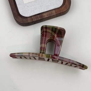 Close-up of a large red and green plaid hair claw clip with glossy finish