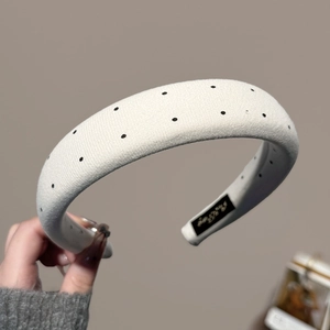 Detailed texture of thick white sponge headband with black polka dots and label