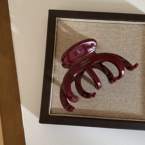 Detail view of handmade French burgundy acetate hair claw on a vintage display board