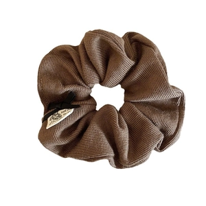 Brown knitted scrunchie with black ribbon bow and With Love label on white background