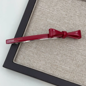 Detailed close-up of glossy red acetate bow hair clip with golden Barrette la France text