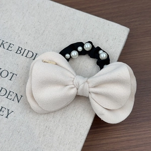 Détail de chouchou noeud en laine avec tissu crème et perles sur l'élastique noir