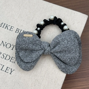 Détail d'un chouchou noeud en laine grise avec perles blanches et pendentif doré chic
