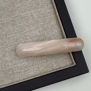 Nahaufnahme der gebogenen Acetat-Haarklammer mit rosa Marmortextur und Sanshine-Logo