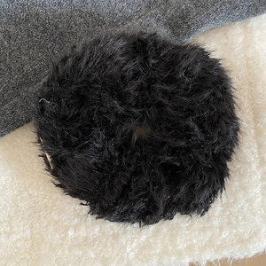 Fuzzy black plush scrunchie in faux fur material for a cozy winter hairstyle