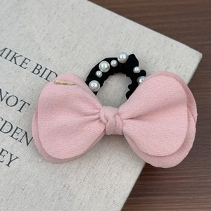 Détail du chouchou nœud en laine rose avec perles blanches et détail en métal doré
