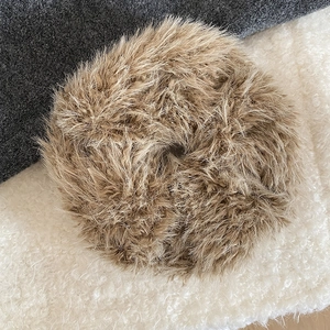 Detail of plush faux fur scrunchie in dark khaki on soft winter textured fabrics