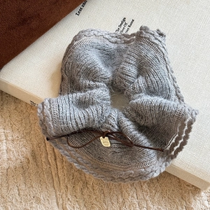 Chic grey knitted hair scrunchie with a brown bow and gold metal tag on a book