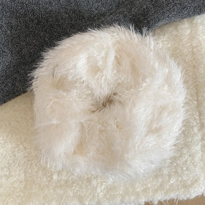 Close-up of white plush faux fur scrunchie on warm winter textured fabrics