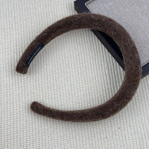 Maillard brown plush headband with handmade label on beige woven background texture