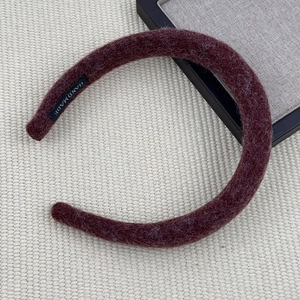 Detail view of handmade dark burgundy felt headband with plush wool texture and inner label