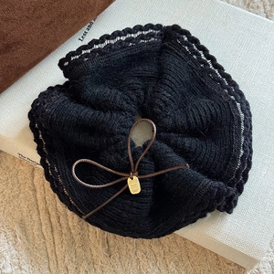 Close-up of black knit scrunchie with brown bow detail and tiny gold charm on fabric