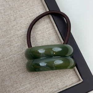 Detail of high-elasticity hair tie with dark green resin beads on linen tray texture