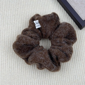 Close-up of fluffy brown plush hair scrunchie with a white Made Beautiful Girl woven label