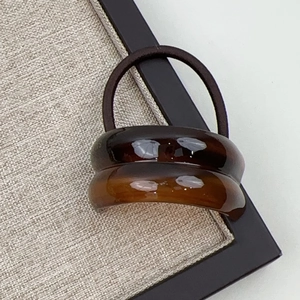 Close-up of minimalist resin hair tie with amber geometric curved accent and elastic band