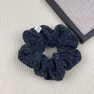 Detail of dark grey plush scrunchie with soft faux lamb wool texture and small woven label