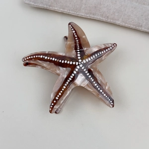 Detail showing the brown marbled starfish hair claw clip with golden spring and teeth