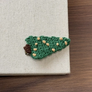 Detailed view of a handmade crochet Christmas tree hair clip with a silver metal BB clip