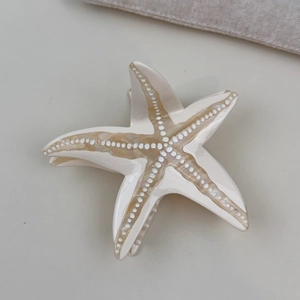 Detailed macro view of the starfish acetate hair claw clip with elegant shell texture patterns
