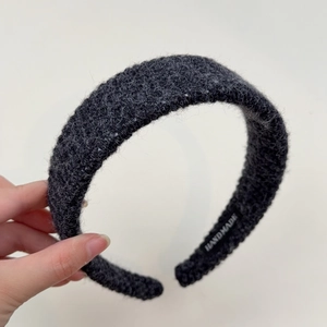 Close-up of thick charcoal grey knitted headband featuring a handmade fabric label detail