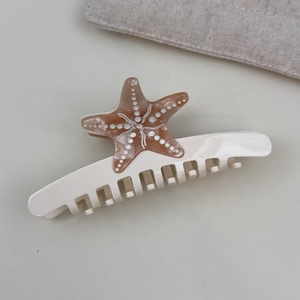 Detailed top view of a starfish claw clip featuring amber acetate with white polka dots