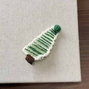 Close-up of handmade crochet Christmas tree hair clip with festive green knit pattern