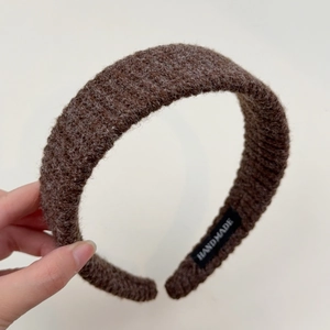 Close-up of thick coffee brown knitted headband with handmade label and soft wool texture