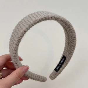 Detail of oatmeal knitted headband featuring thick ribbed texture and handmade label