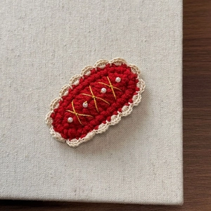 Detailed macro view of handmade red crochet hair clip with lace trim and small white pearls