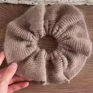 Chouchou géant tricoté et pelucheux beige marron sur un fond de bois sombre et rustique