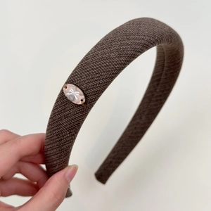 Close-up of brown twill fabric headband with thick sponge and oval bow emblem