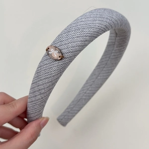 Close-up of gray knitted fabric headband featuring a small amber butterfly plaque