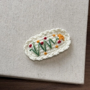 Detailed close-up of handmade crochet hair clip with colorful floral embroidery