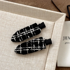 Macro detail of black and white tweed hair clips with elegant gold thread weaving