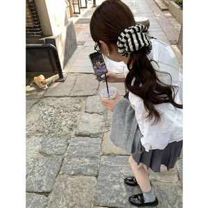Classic black and white striped knitted scrunchie shown in a stylish outdoor setting
