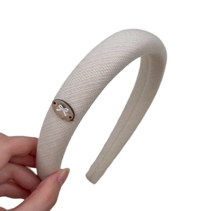 Retro cream beige padded headband with butterfly emblem on thick fabric texture