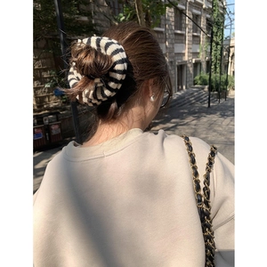 Knitted zebra striped hair scrunchie shown in a stylish ponytail on a female model