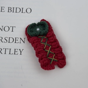 Detailed close-up of a handmade crochet Christmas tree hair clip with white pearl detail