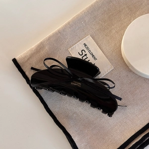Elegant black acetate hair claw with a silk ribbon bow and gold lettering detail