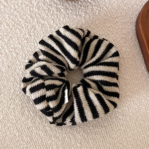 Detail of black and white striped knitted scrunchie with soft wool texture and small tag