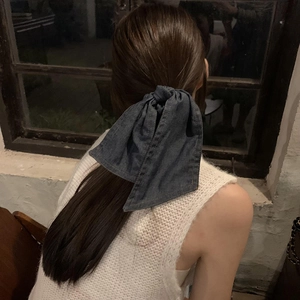 Vintage dark blue denim bow scrunchie for women tied on ponytail in retro style