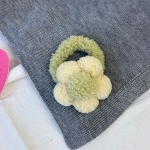 Vue détaillée du chouchou fleur en peluche, fabriqué en polaire teddy verte et beige