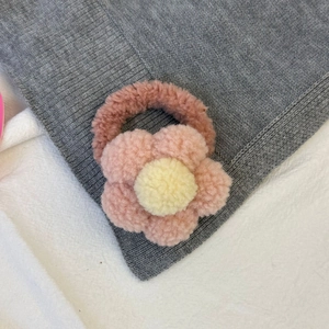 Gros plan sur un chouchou fleur en peluche rose et jaune à la texture douce