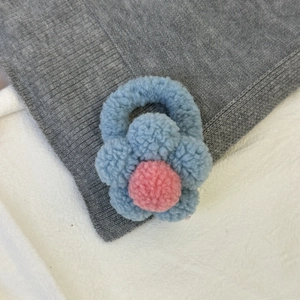 Détail de l'élastique fleur en peluche avec pétales bleus et pompon rose au centre