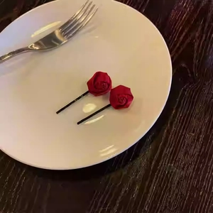 Primo piano di due fermagli per capelli a forma di rosa in seta rossa con clip in metallo