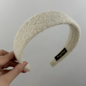 Détail du serre-tête en peluche blanc cassé avec étiquette de marque tissée
