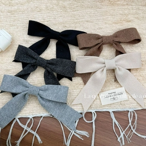 Lot de cinq barrettes à nœuds en tricot élégantes aux tons neutres sur un fond texturé